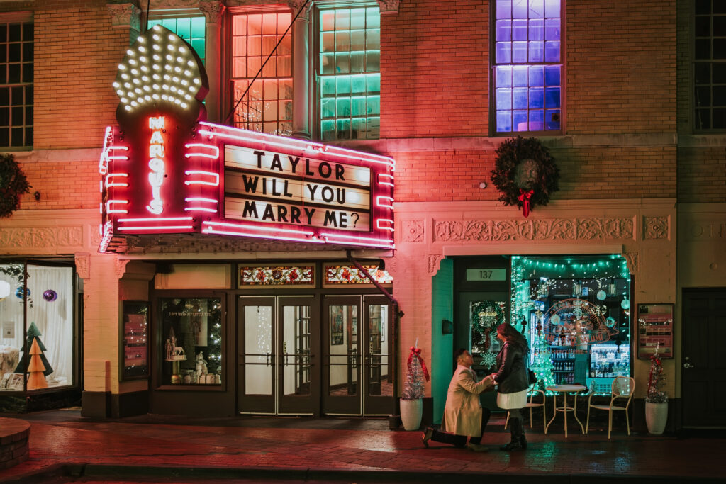 Man proposing to woman at Northville’s downtown theater during a winter sunset