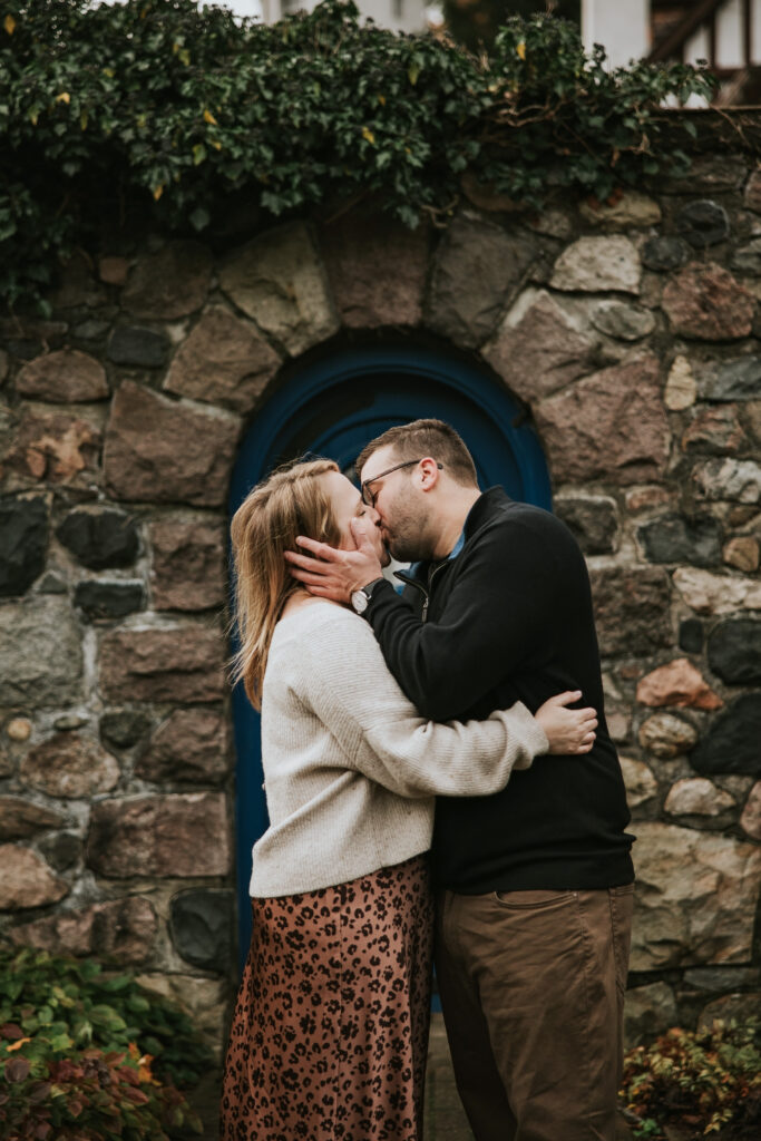 Couple kissing in front of the stone garden walls at their Cranbrook engagement session.  