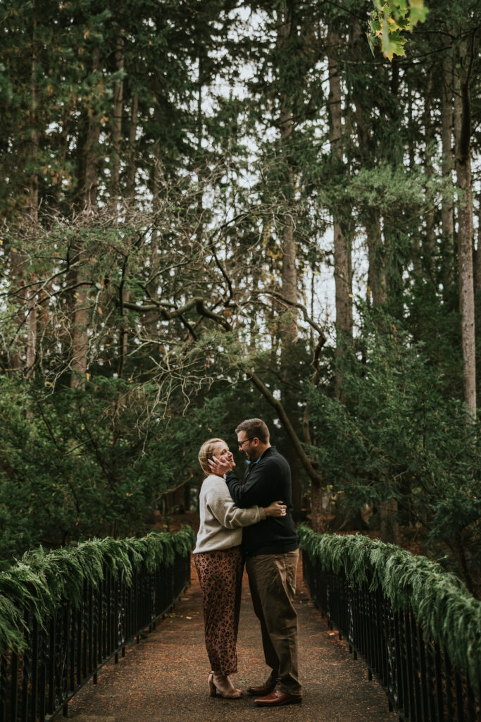 Couple standing close under golden autumn leaves at Cranbrook Gardens.