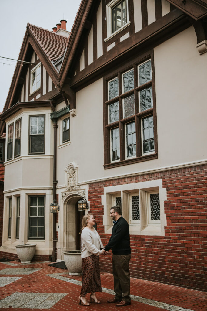 Couple holding hands near Cranbrook House surrounded by fall colors.