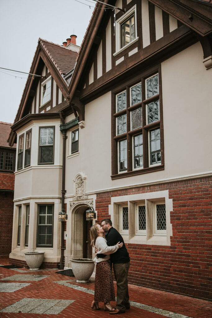 Couple embracing in front of Cranbrook House during their engagement session.