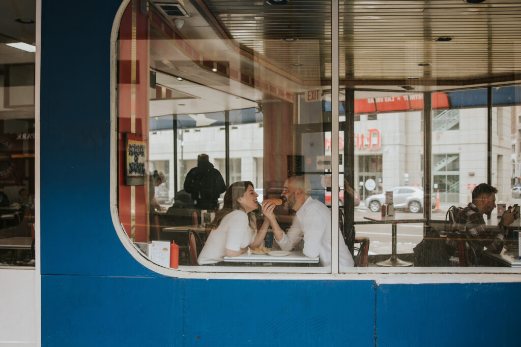 Couple enjoying a candid moment at American Coney Island during their Detroit Winter Engagement Session.