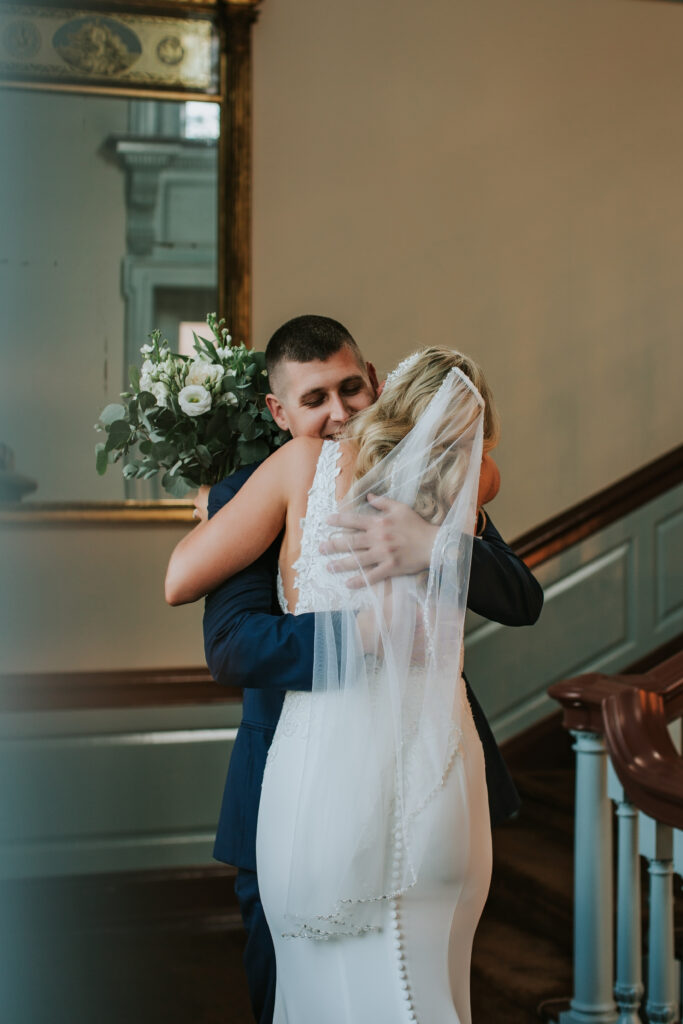 Romantic first look between bride and groom in the front foyer of Lovett Hall, Henry Ford Museum, Michigan.