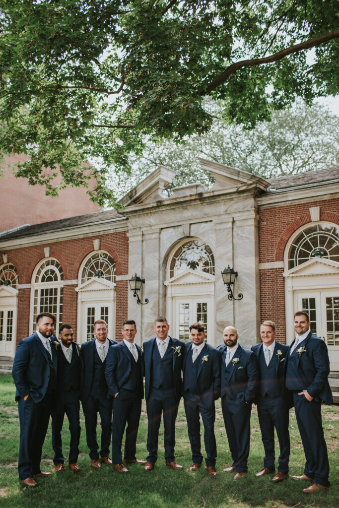 Groom and his groomsmen posing outside Lovett Hall, dressed in matching suits, celebrating the wedding day.