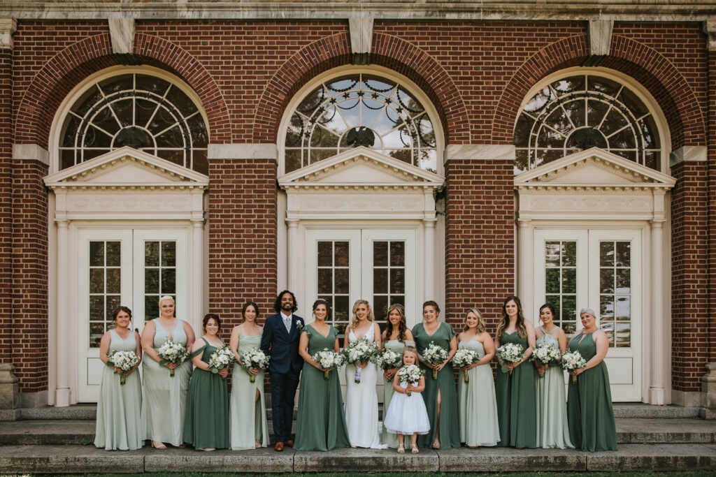 Bridal party posing outside Lovett Hall in Michigan, with the bride and bridal attendants celebrating Amanda and Mitchell’s wedding.