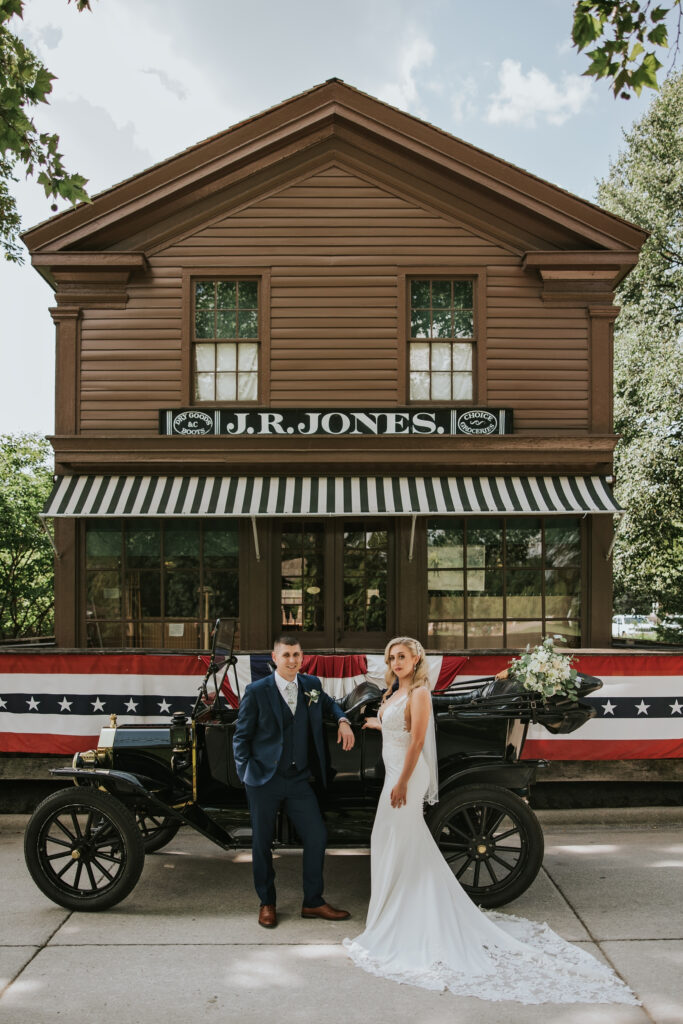 Wedding couple posing in front of historic buildings at Greenfield Village, capturing a timeless wedding moment.