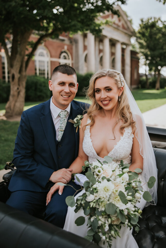 Bride and groom posing in a vintage Model T car at Greenfield Village for their Lovett Hall wedding portraits.