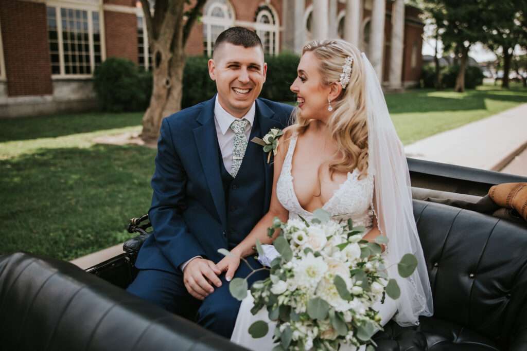 Newlyweds laughing together riding in the Model T within Greenfield Village, capturing a romantic moment.