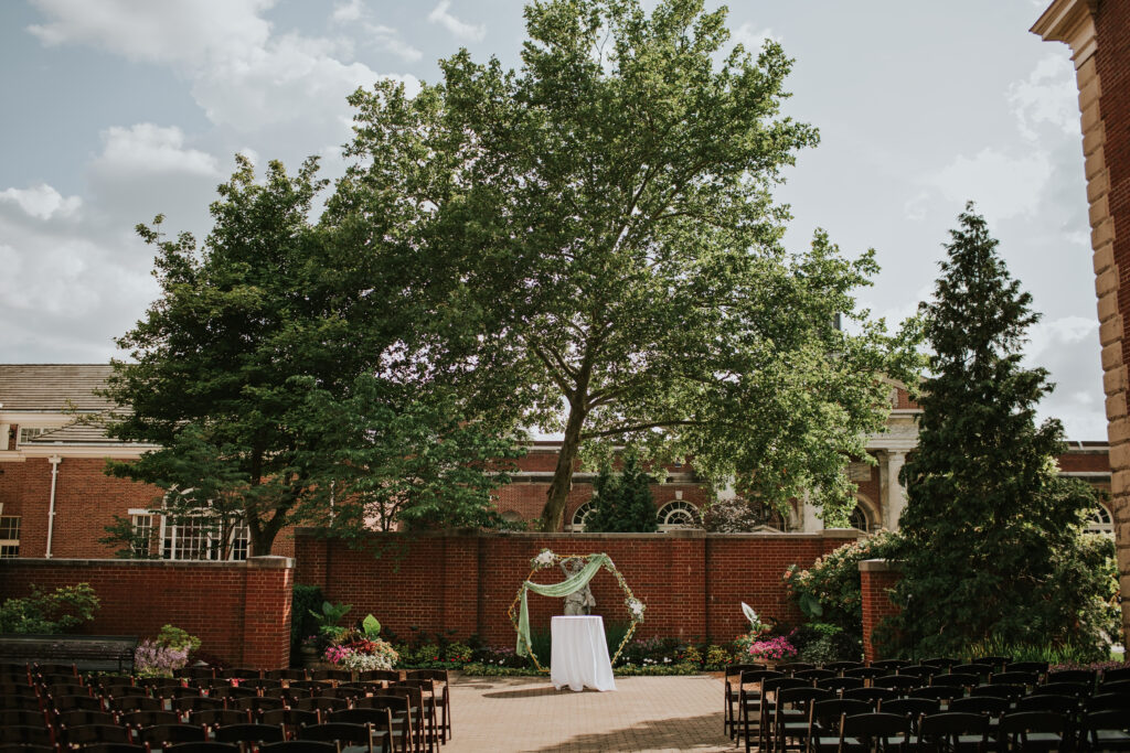 Wide shot of a wedding ceremony setup at Lovett Hall, featuring a floral arch and neatly arranged chairs awaiting guests.