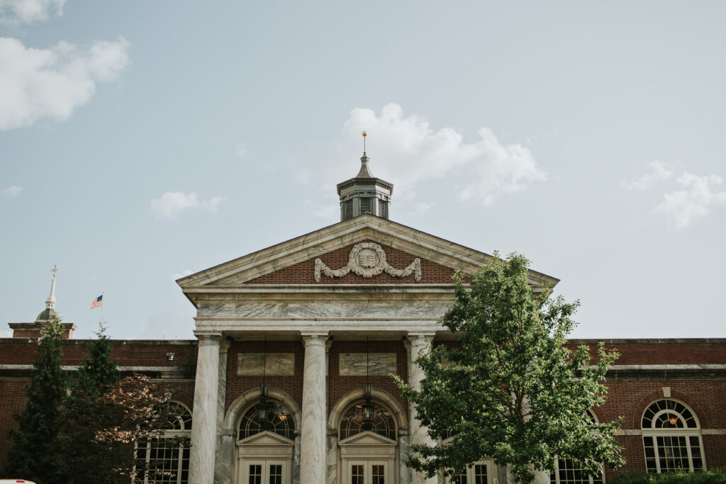 Lovett Hall surrounded by greenery on a sunny day, offering a classic and picturesque backdrop for Amanda and Mitchell’s wedding.