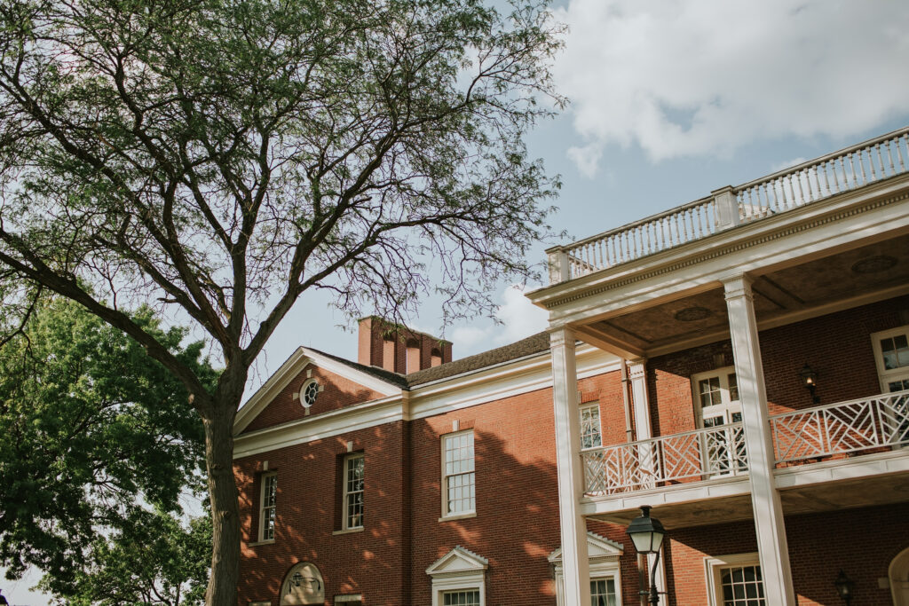 Wide view of Lovett Hall’s stately exterior at Henry Ford Museum, showcasing its timeless architecture and lush landscaping.