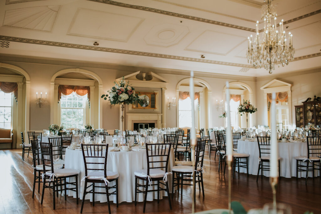 Elegant ballroom at Lovett Hall set for a wedding reception, featuring round tables, floral centerpieces, and a grand chandelier.