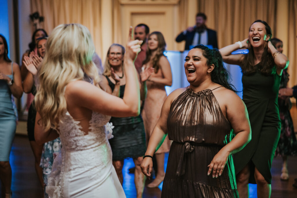 Guest sharing laughter with the bride during the reception at Lovett Hall, Henry Ford Museum.