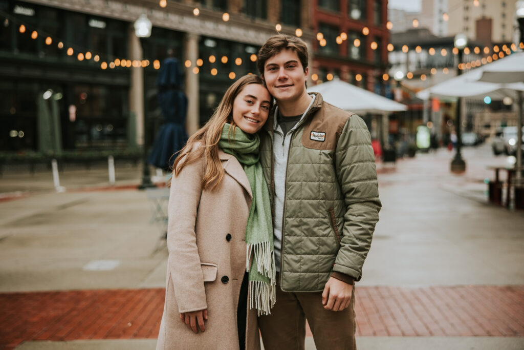 Couple posing with downtown Detroit’s architecture during their rainy engagement session.