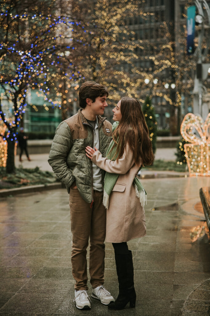 Kate and Tyler smiling as they explore Campus Martius during their rainy engagement session.