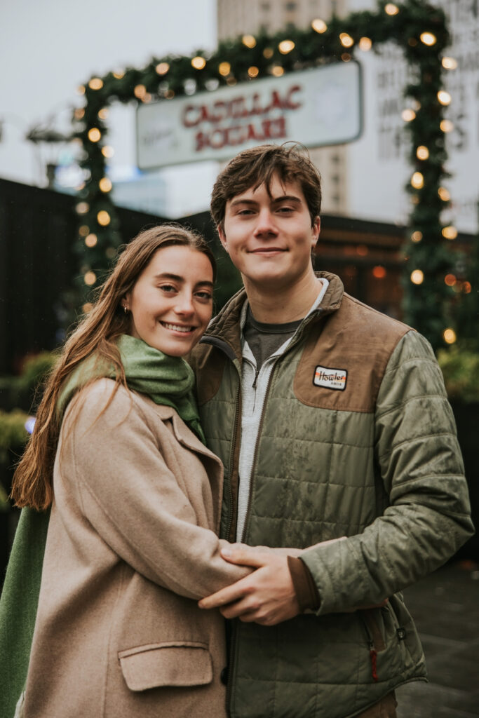 Couple capturing the holiday spirit in Cadillac Square, Detroit, during their engagement session.