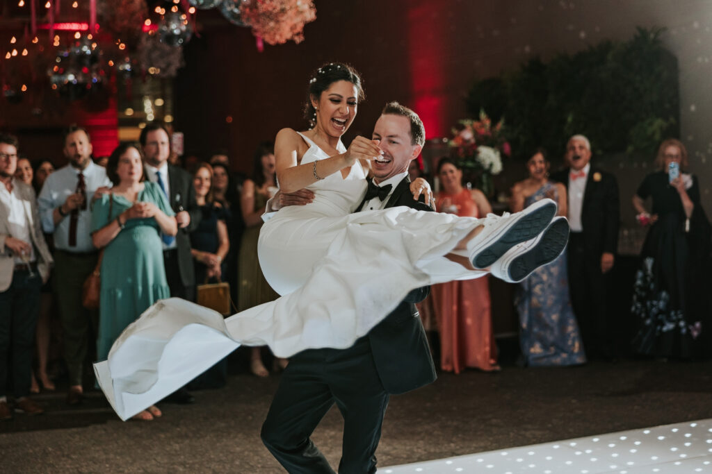 Groom lifts bride in a spin while they share a dance at Waterview Loft, Detroit wedding venue.