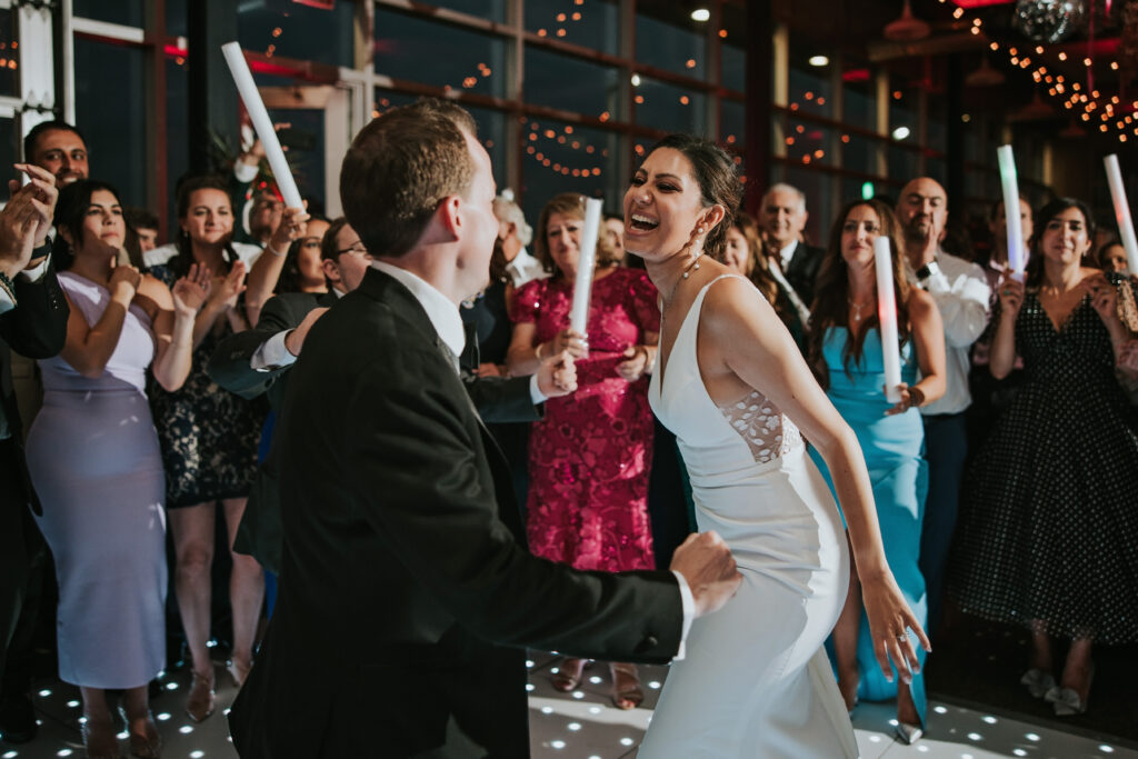 Bride and groom dance on a packed dance floor at their Waterview Loft Detroit summer wedding.