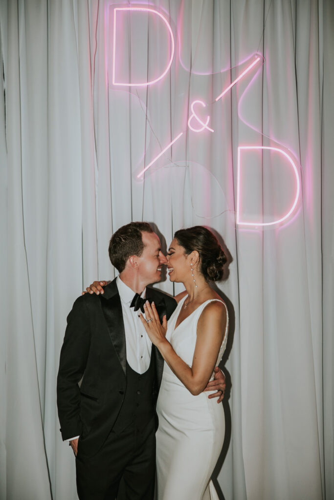 Bride and Groom snuggle below their neon sign at their Waterview Loft Detroit wedding reception.