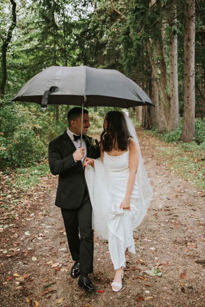 Bride and groom laughing together under a clear umbrella on their wedding day | Wedding Planning Tips