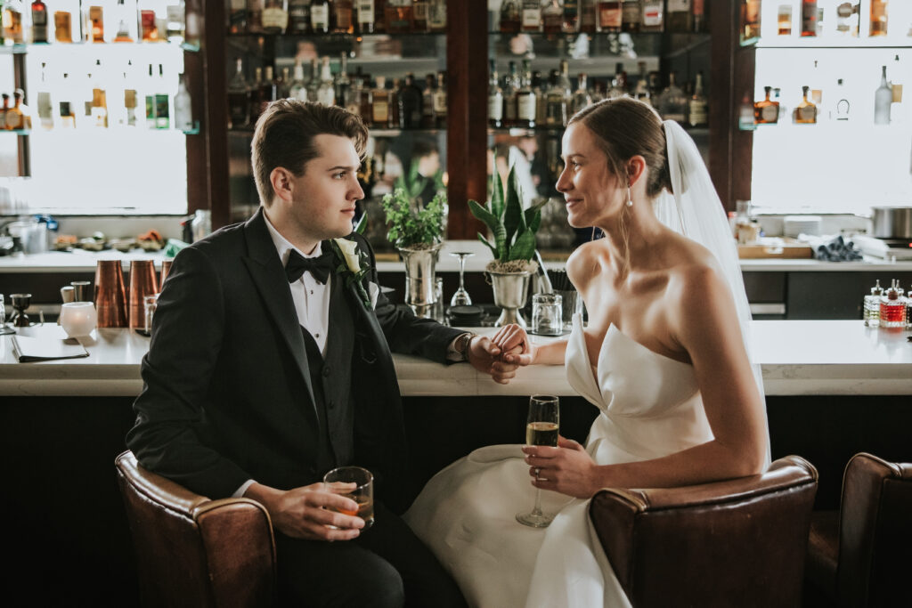 Bride and groom sitting at the Monarch Club bar, enjoying a quiet moment during their wedding portraits | Wedding Planning Tips