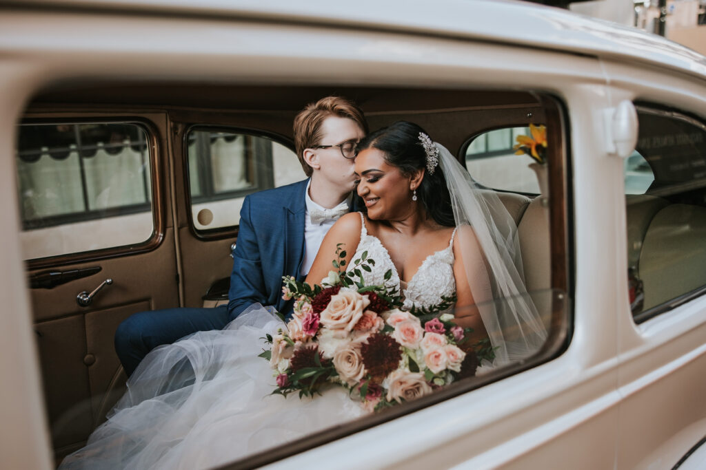 Bride and groom snuggling in a vintage car outside the Colony Club in Detroit | Wedding Planning Tips