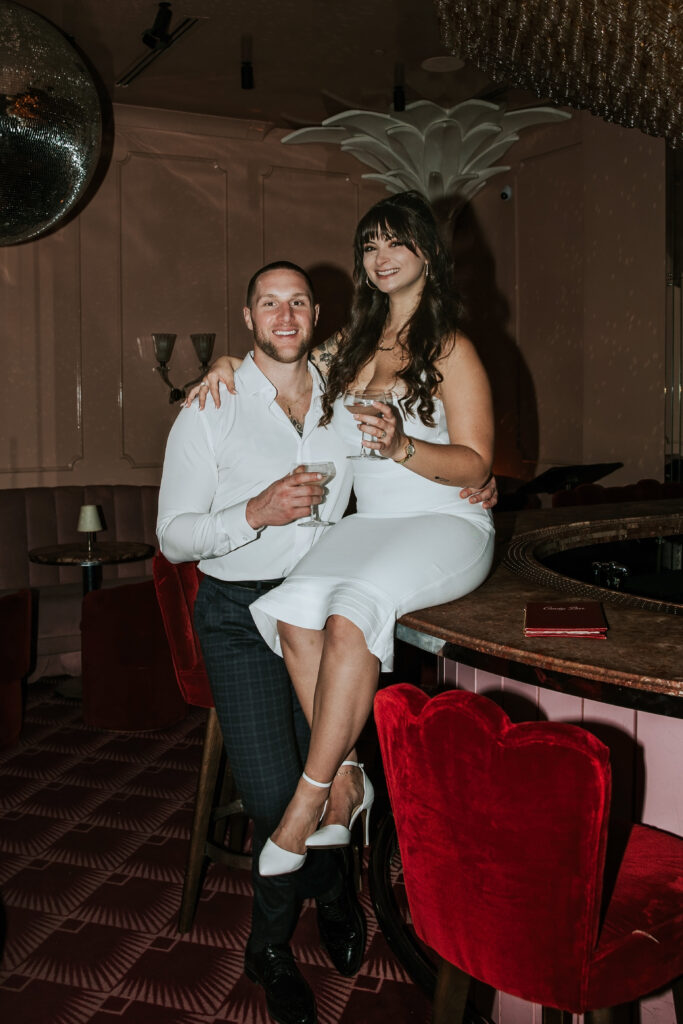 Couple sharing a sweet laugh surrounded by stylish decor during a Candy Bar Detroit Engagement session in a modern Detroit lounge.