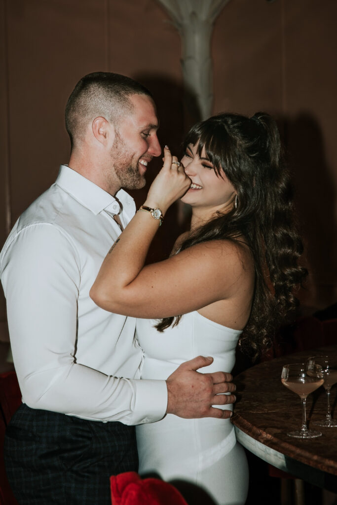 Candid shot of a couple sharing a tender moment during a Candy Bar Detroit Engagement session inside a modern Detroit lounge.