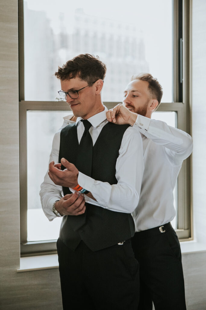 Groom laughing with groomsmen in a suite at the Westin Book Cadillac