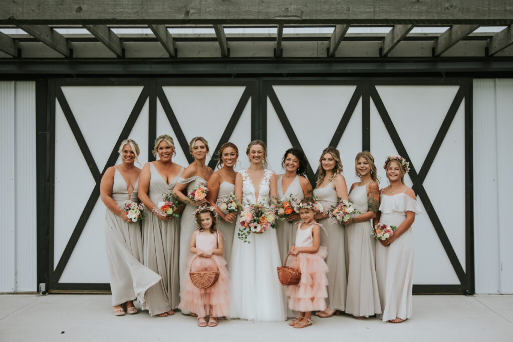 Laughing bride surrounded by bridesmaids in elegant dresses, joyous Traverse City moment.