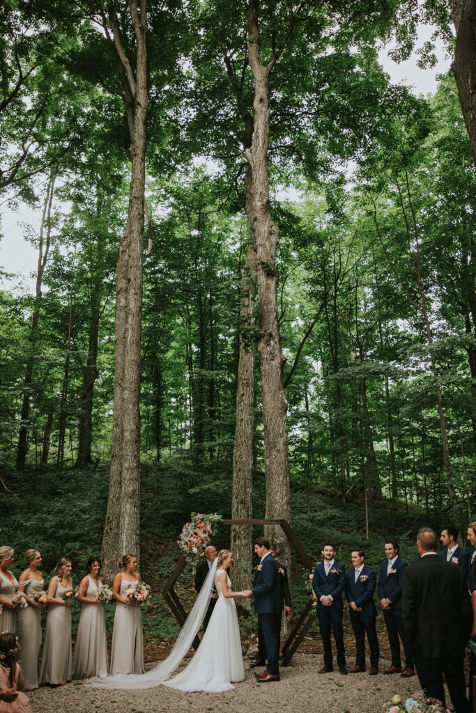 Bride and groom exchanging vows under sunlit woodland, Traverse City Wedding Photography.