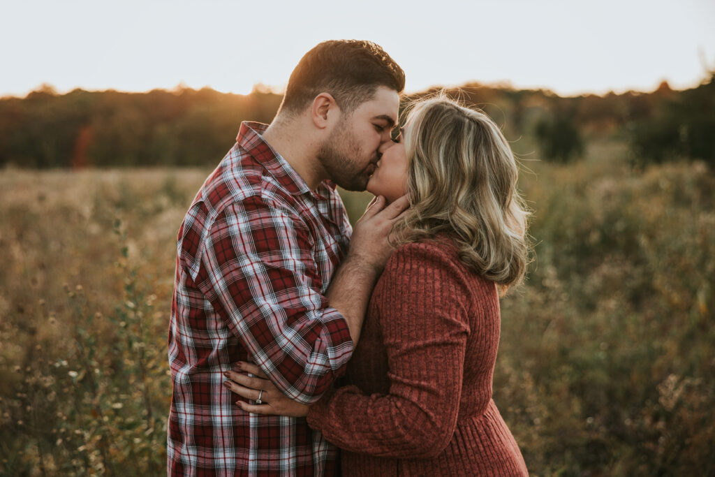 Bride and groom kissing in a field while the sun sets at their Kensington Metropark Engagement Session